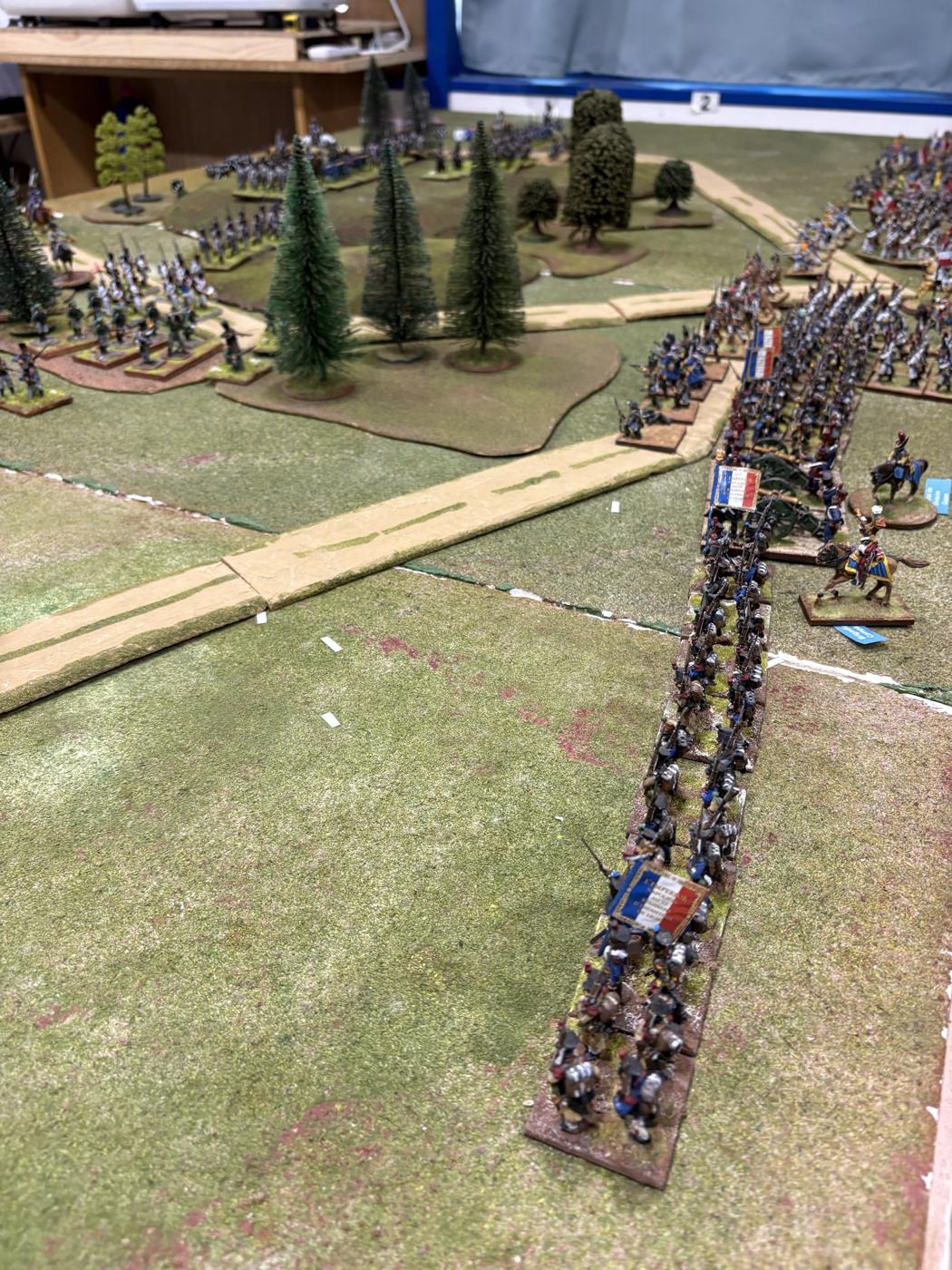 Una larga columna francesa con banderas avanzando junto al camino hacia las alturas