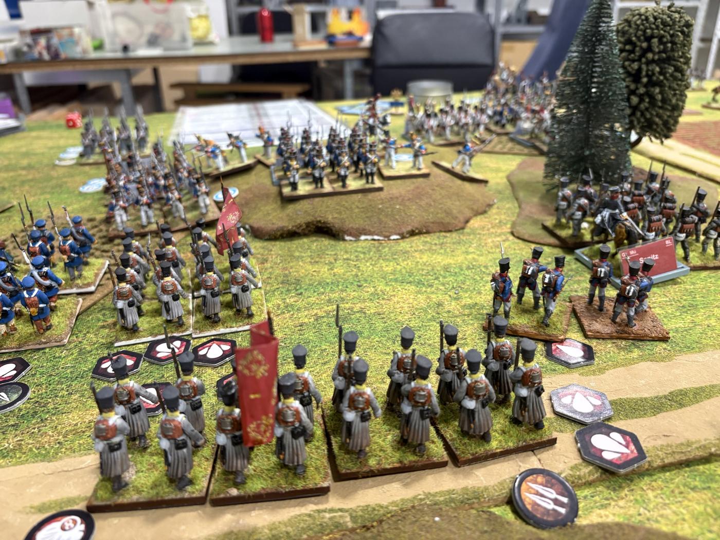 Batallones prusianos con capote gris y bandera roja formados frente a las columnas francesas, con marcadores de bajas